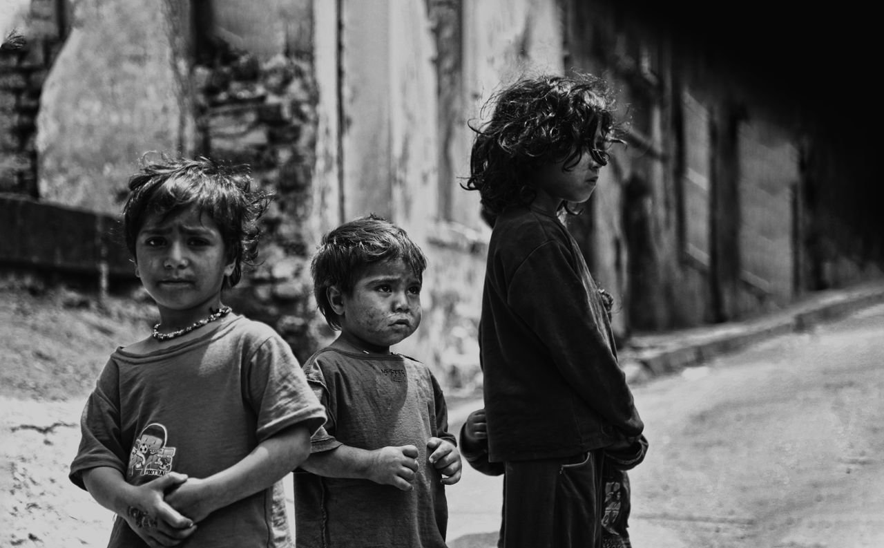 Black and white photo of children on a weathered street, conveying emotion.